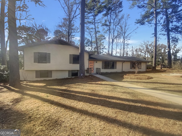 tri-level home featuring central AC unit and a front yard