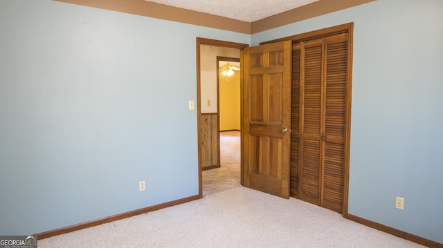 unfurnished bedroom with a textured ceiling, a closet, carpet flooring, and baseboards