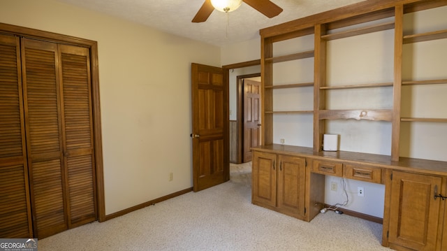 office featuring light carpet, baseboards, a ceiling fan, a textured ceiling, and built in desk