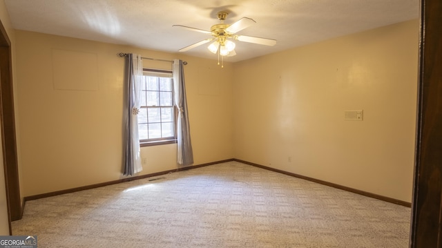 spare room with light colored carpet, ceiling fan, visible vents, and baseboards