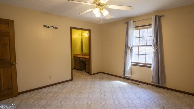 unfurnished bedroom with visible vents, a ceiling fan, light carpet, connected bathroom, and baseboards