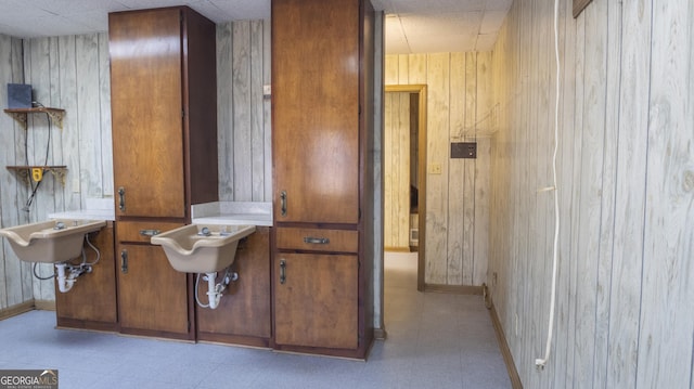 bathroom with a paneled ceiling, wooden walls, baseboards, and tile patterned floors