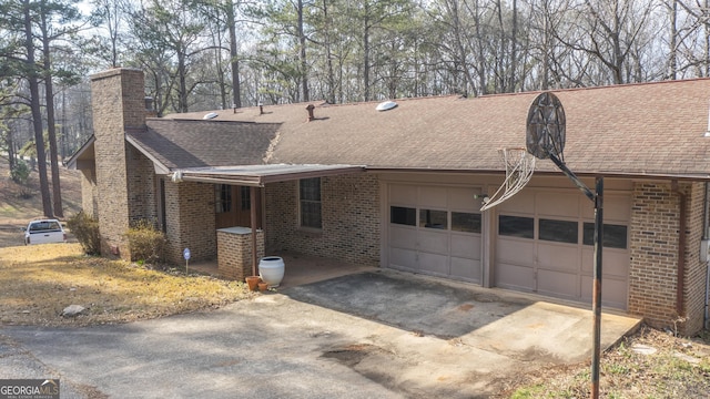 exterior space featuring brick siding, an attached garage, and roof with shingles