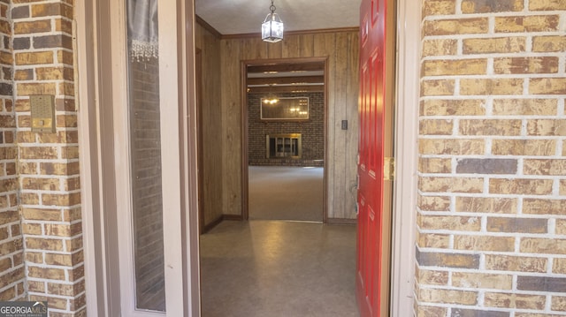 corridor with finished concrete flooring, brick wall, wooden walls, and ornamental molding