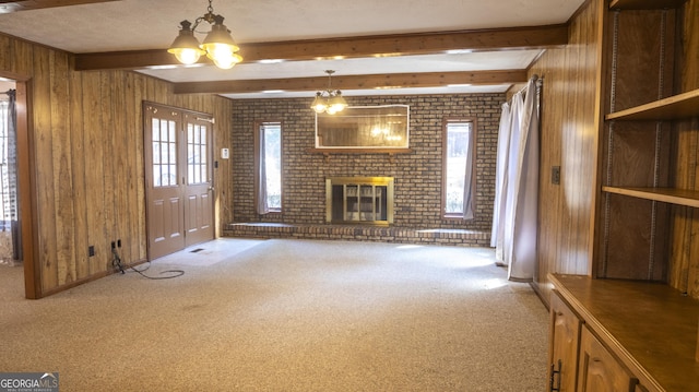 unfurnished living room with carpet, beam ceiling, wooden walls, and a brick fireplace