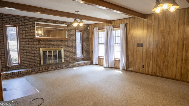 unfurnished living room with carpet floors, beam ceiling, a fireplace, and wooden walls