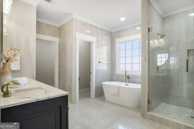 bathroom with a stall shower, a freestanding tub, crown molding, toilet, and tile walls