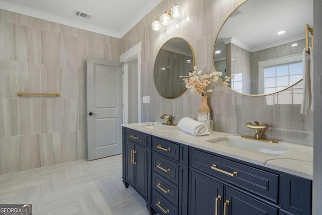 bathroom featuring a sink, crown molding, visible vents, and tile walls