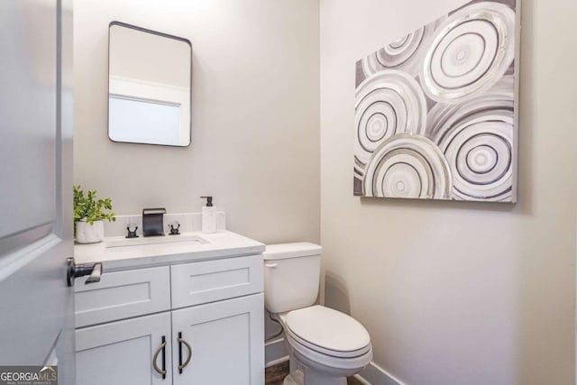 bathroom featuring baseboards, toilet, and vanity