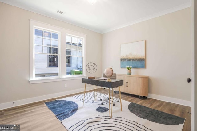 office with baseboards, ornamental molding, visible vents, and wood finished floors