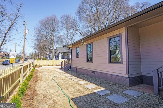 view of home's exterior with crawl space, fence, and a residential view