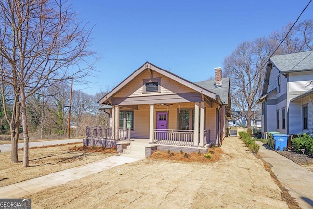 bungalow-style house featuring a chimney and covered porch