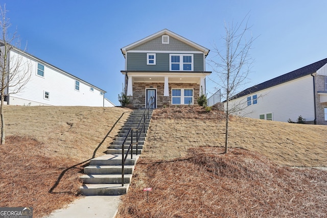 view of front of home with stairway, a porch, and stone siding