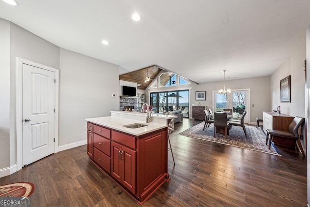 kitchen with a notable chandelier, dark wood-type flooring, a sink, open floor plan, and dark brown cabinets