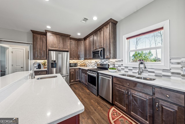 kitchen with stainless steel appliances, visible vents, a sink, and dark wood-type flooring