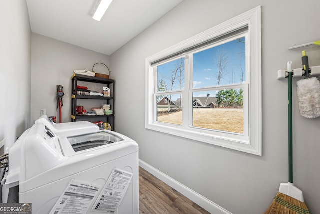 clothes washing area featuring laundry area, baseboards, separate washer and dryer, and wood finished floors