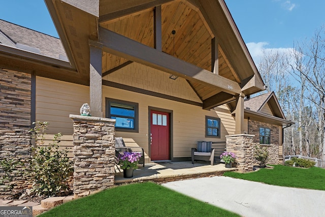 doorway to property featuring a shingled roof and a porch