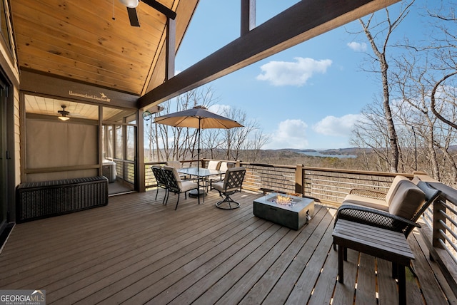 deck with a fire pit, outdoor dining space, and a ceiling fan