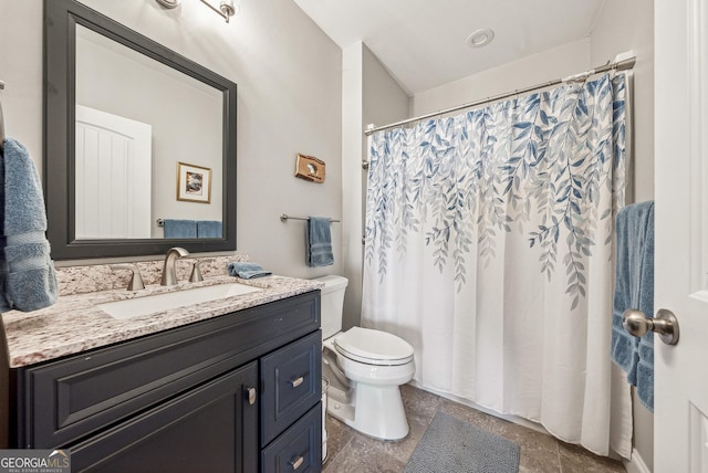 bathroom featuring toilet, stone tile floors, a shower with shower curtain, and vanity