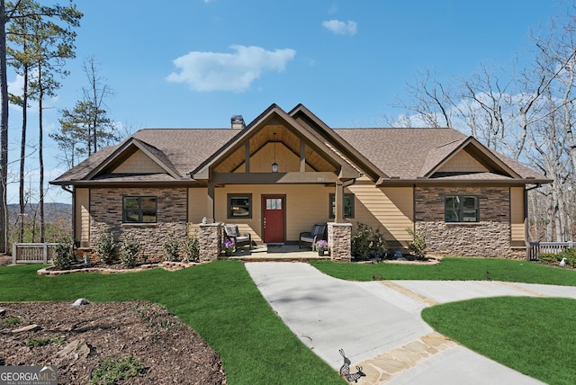 craftsman house with stone siding, a chimney, and a front yard