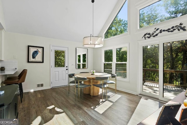 dining area with high vaulted ceiling, baseboards, visible vents, and wood finished floors