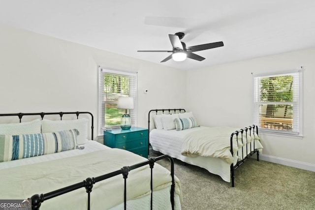 carpeted bedroom with a ceiling fan, multiple windows, and baseboards