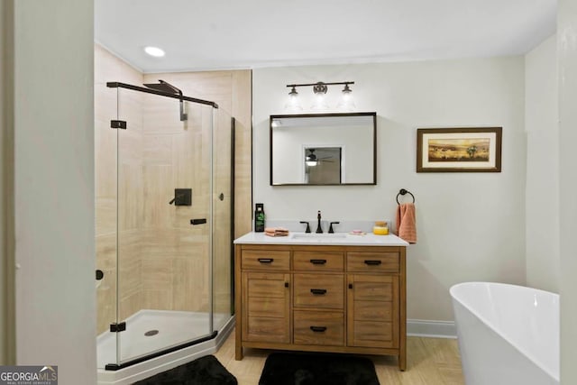 full bath with a stall shower, baseboards, a freestanding bath, and vanity