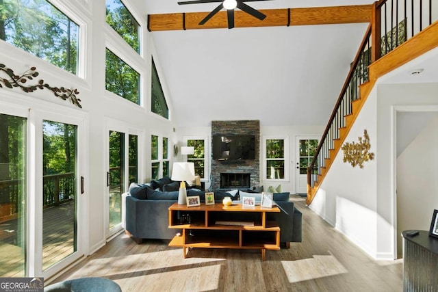 living room with a stone fireplace, plenty of natural light, and a high ceiling