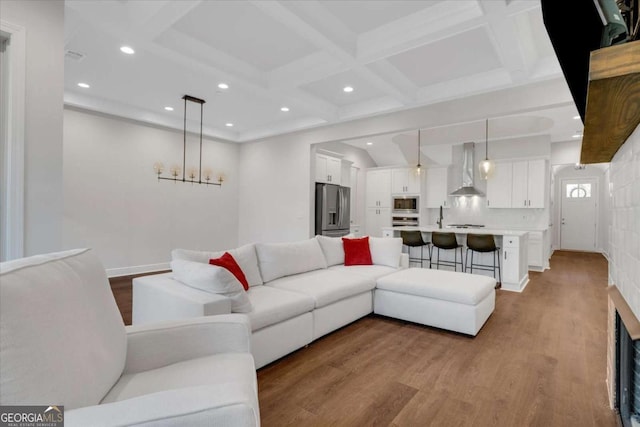 living area with beam ceiling, coffered ceiling, wood finished floors, and recessed lighting