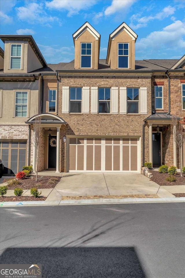 view of property featuring a garage, brick siding, and driveway