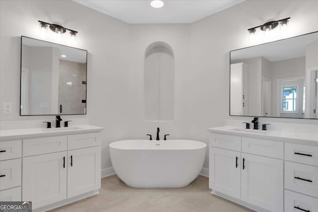 full bathroom featuring a freestanding tub, two vanities, and a sink