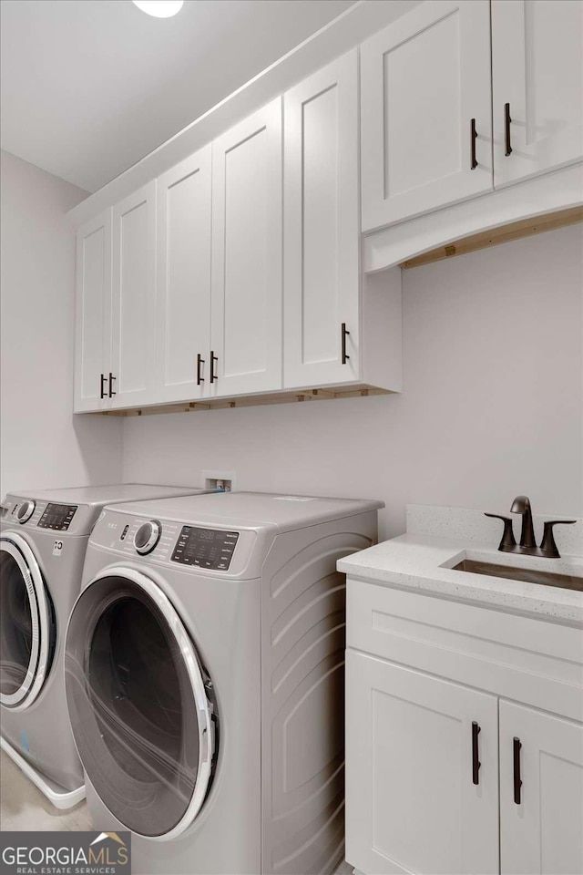 laundry area with cabinet space, independent washer and dryer, and a sink