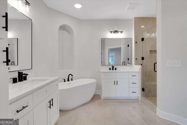 full bathroom featuring a stall shower, a freestanding tub, two vanities, and a sink