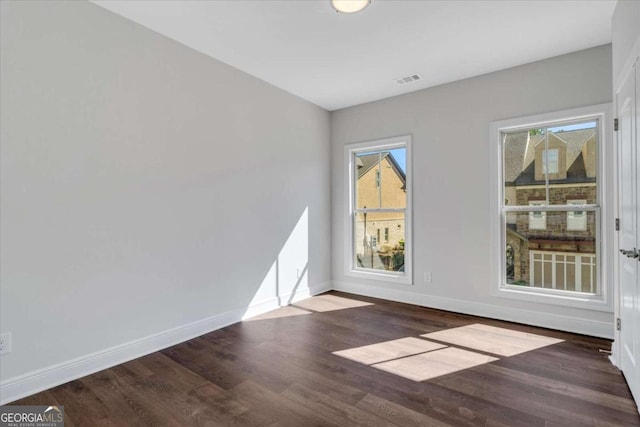 empty room featuring visible vents, baseboards, and wood finished floors