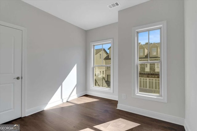 spare room featuring baseboards, visible vents, and wood finished floors