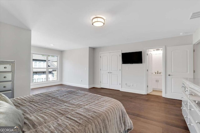 bedroom with visible vents, ensuite bathroom, baseboards, and wood finished floors