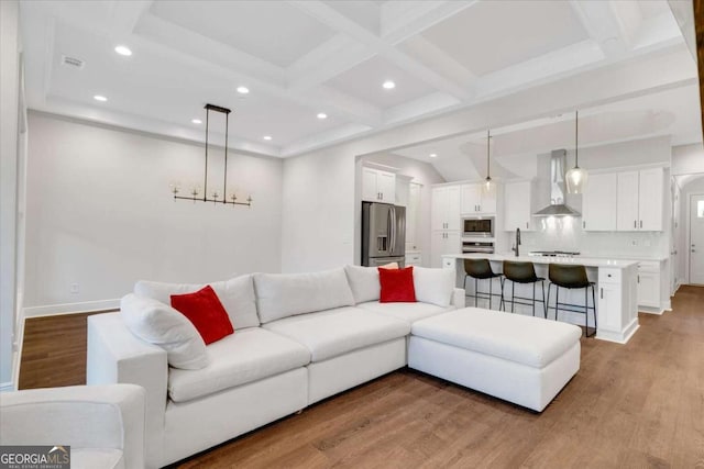 living room featuring light wood-type flooring, coffered ceiling, beam ceiling, and recessed lighting