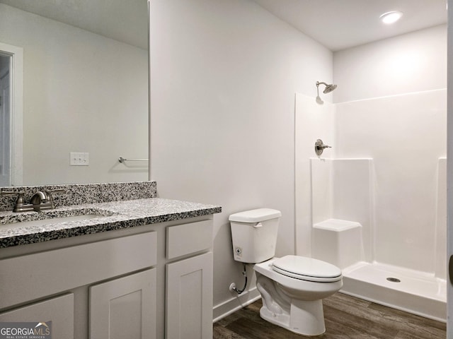 full bathroom featuring baseboards, toilet, wood finished floors, walk in shower, and vanity