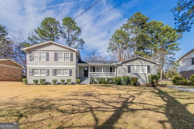 view of front of home featuring brick siding, a porch, and a front yard