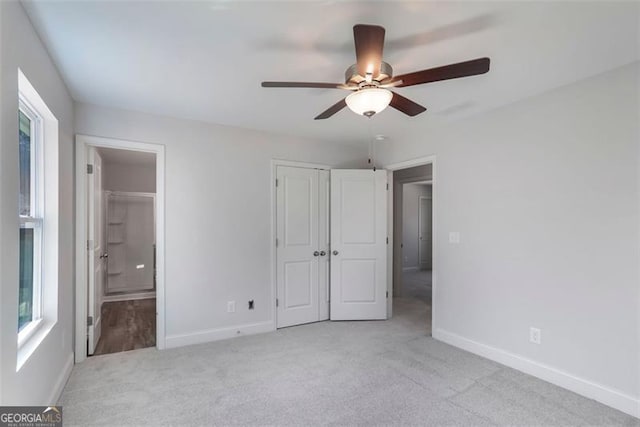 unfurnished bedroom with ceiling fan, baseboards, carpet flooring, and ensuite bathroom