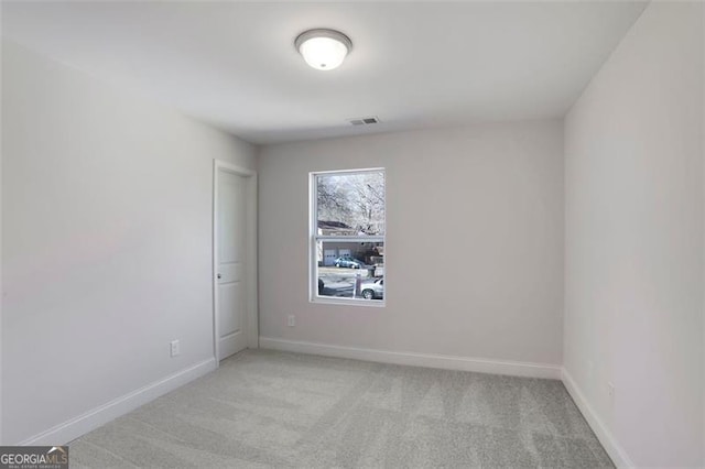 spare room with light colored carpet, visible vents, and baseboards