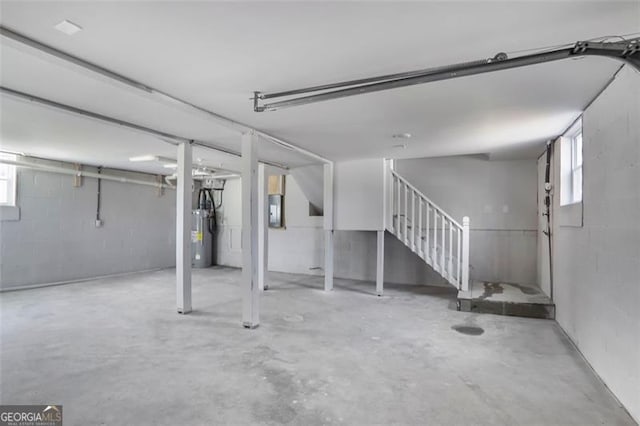 below grade area with electric panel, plenty of natural light, stairs, and concrete block wall