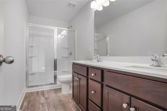 full bath with visible vents, a sink, a shower stall, and wood finished floors