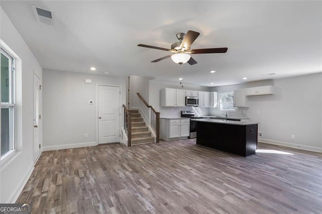 kitchen featuring stainless steel appliances, wood finished floors, a kitchen island, visible vents, and white cabinets