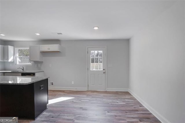 kitchen featuring light stone counters, light wood-style floors, a wealth of natural light, and baseboards