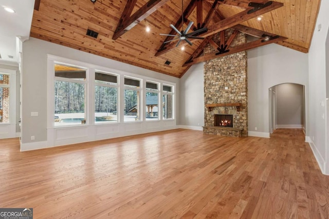 unfurnished living room featuring wood ceiling, beamed ceiling, light wood-style floors, a fireplace, and high vaulted ceiling