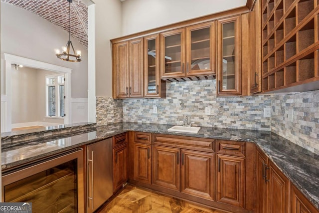 kitchen featuring wine cooler, brown cabinets, and dark stone countertops