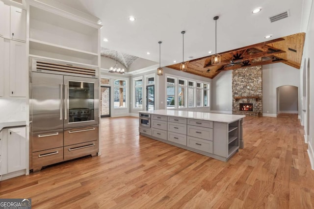 kitchen featuring open shelves, gray cabinets, open floor plan, light wood-type flooring, and built in refrigerator