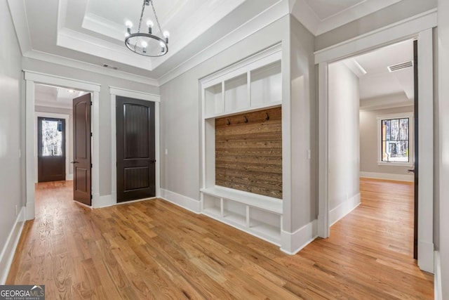 mudroom with a notable chandelier, visible vents, light wood-type flooring, a raised ceiling, and crown molding