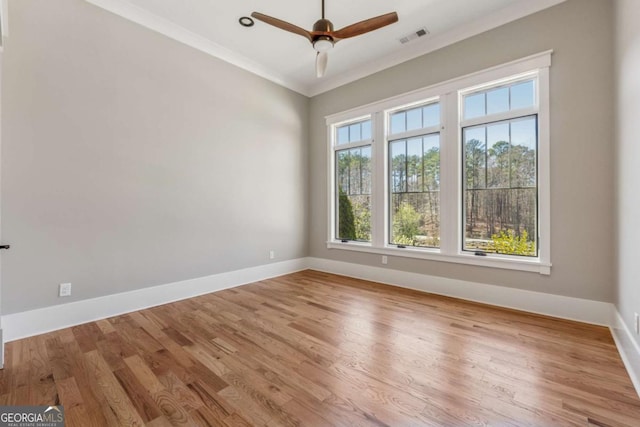 empty room featuring baseboards, visible vents, a ceiling fan, ornamental molding, and wood finished floors